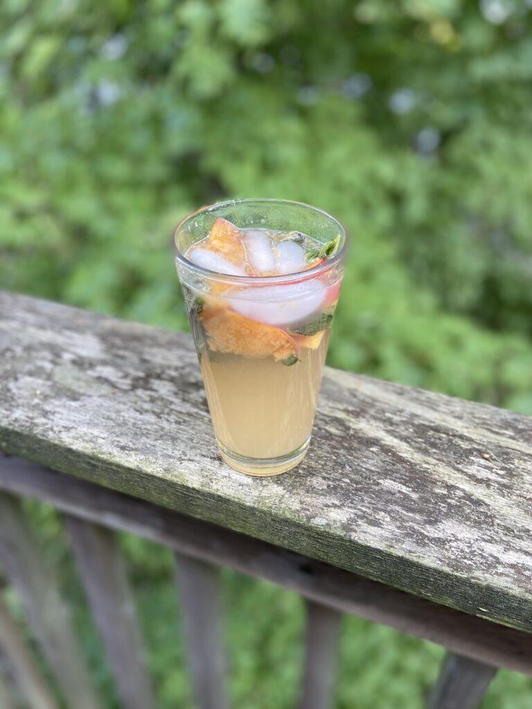 peach mint tea seltzer on a wooden railing