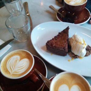 chocolate coffee cake next to cups of coffee. 